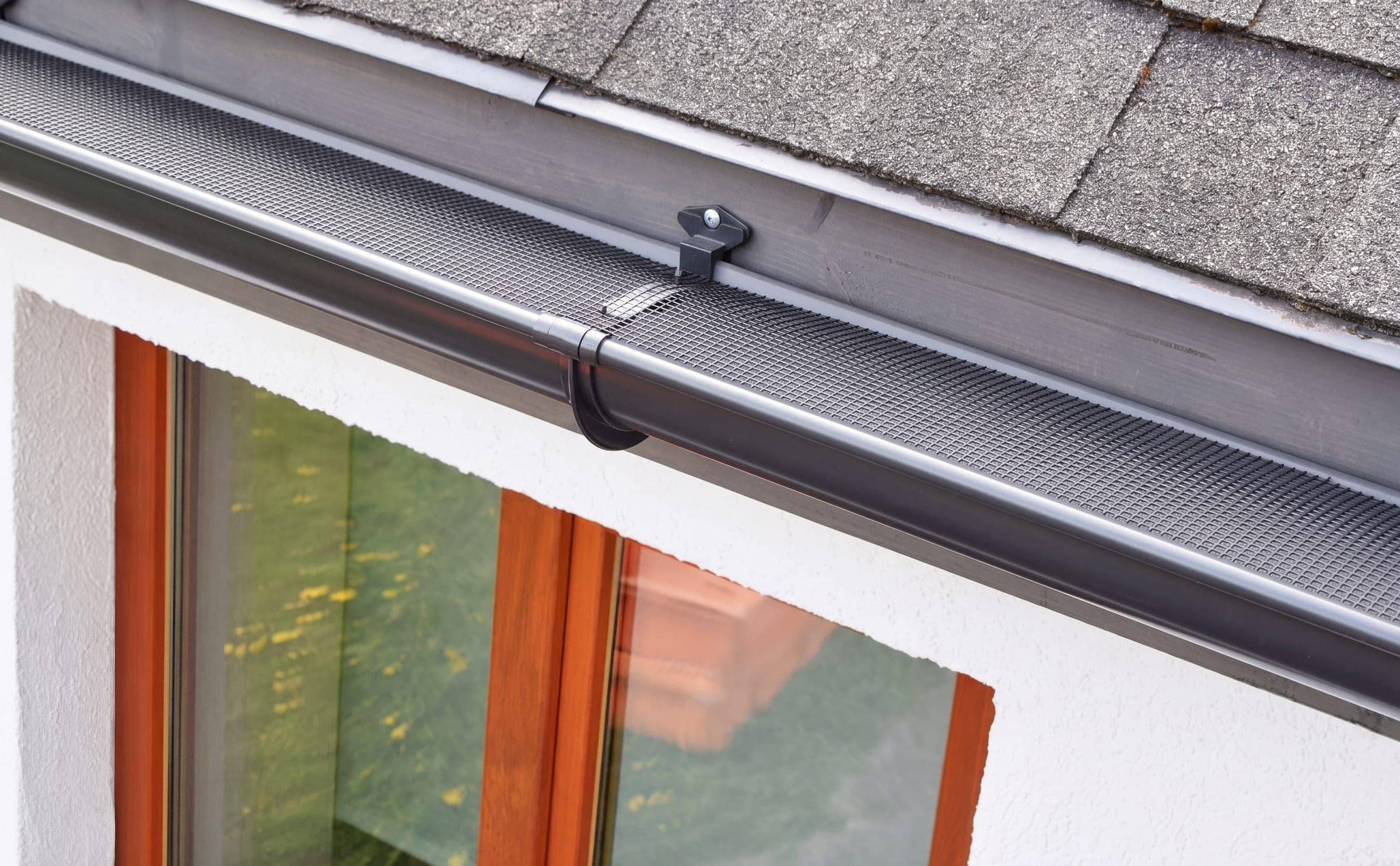 Guttering after cleaning, a mesh guard running clear along its whole length above a timber window